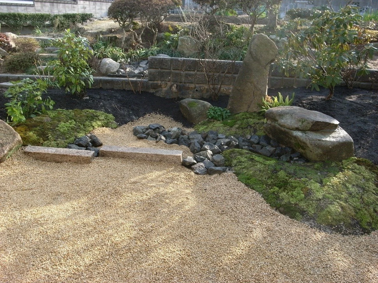 剪定された庭木の葉影が石畳に落ちる夕方の住宅アプローチ